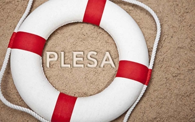 A life preserver with "PLESA" written on the sand beneath it.