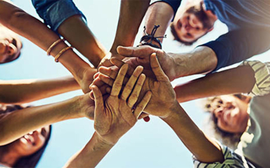 A group of people standing in a circle with their hands in the middle.