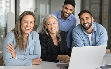 Business professionals at a desk with an open laptop.