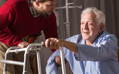 A man helping an elderly gentleman with his walker.