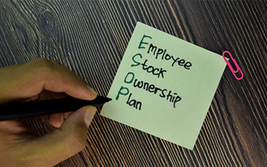 Hand holding a pen writing on a sticky note.