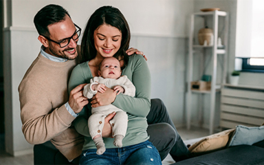 A man, woman and baby on a sofa.