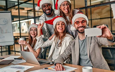 Business professionals wearing Santa hats posing for a selfie.