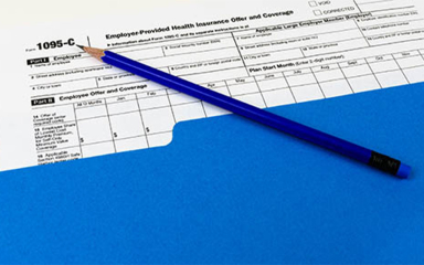 1095-C form in a folder with a pencil on top.