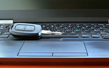 A car key sitting on the keyboard of a laptop.