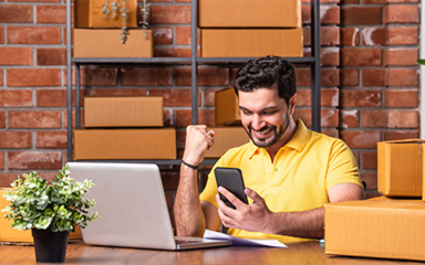A man at a desk making a fist while holding his mobile phone.