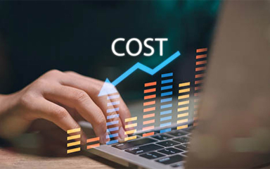 A hand on a laptop with an image of graphs and an arrow trending downward.