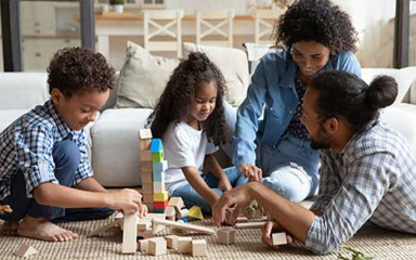 A family playing with wooden blocks while sitting on the floor.