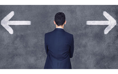 A man wearing a suit looking at a blackboard with a large white arrow pointing right and a large white arrow pointing left.