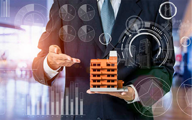 Man in a suit holding a small scale model of a building.