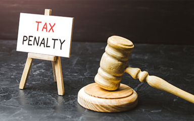 A wooden gavel next to a sign on an easel that says Tax Penalty.