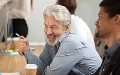 An image of an older worker talking to coworkers.