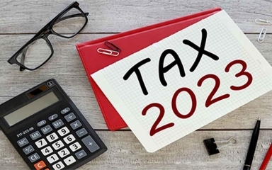 A piece of grid paper with Tax 2023 written across it, surrounded by office supplies.