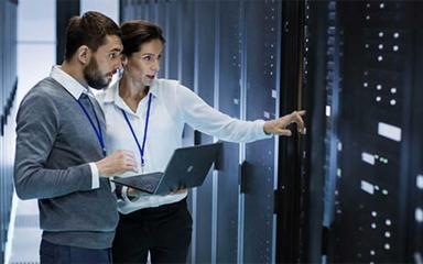 Two people observing a server in a server room.