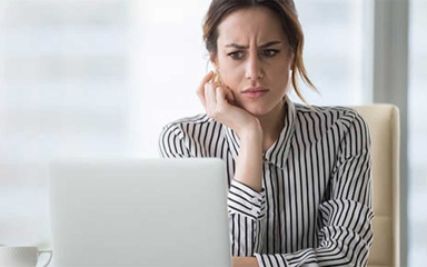 In image of a person looking at her computer, expressing confusion/concern.