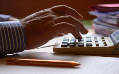 A man's fingers pushing buttons on a calculator.