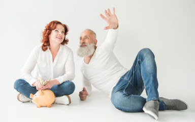 A man and woman sitting next to a piggy bank with the woman holding money.