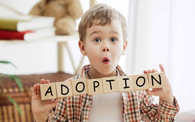 Child holding wooden blocks that spell Adoption