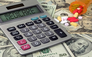 A turned over bottle of pills next to a calculator with "Medicare" written out on the display.
