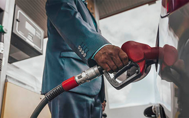 A man in a suit pumping gas.
