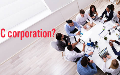 Professionals sitting around a table with paper, pens and laptops.