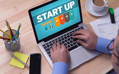Person sitting at a computer with "Start Up" written on the screen.
