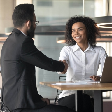 Coworkers shaking hands across a table.