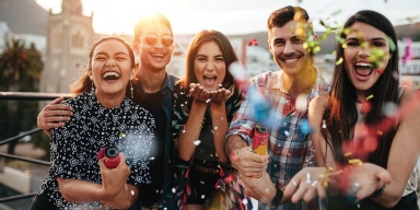 Group of friends outdoors celebrating and throwing confetti.