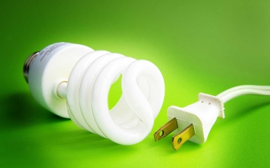 energy efficient lightbulb and wall plug with green glowing background