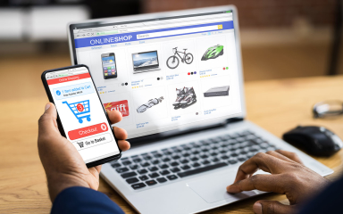 Laptop and cell phone showing a person shopping for and purchasing items online.