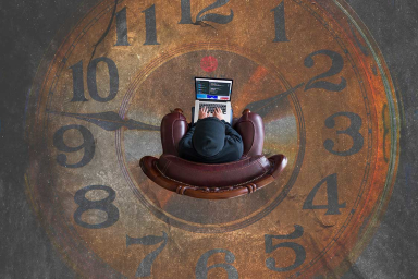 aerial shot of person sitting in chair with laptop and distressed clock image on the ground below