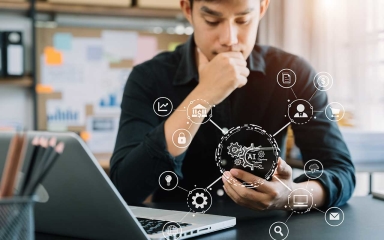 A man holding his chin, looking at his phone.