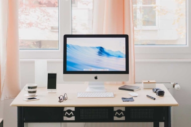iMac on desk with iPhone and coffee cup