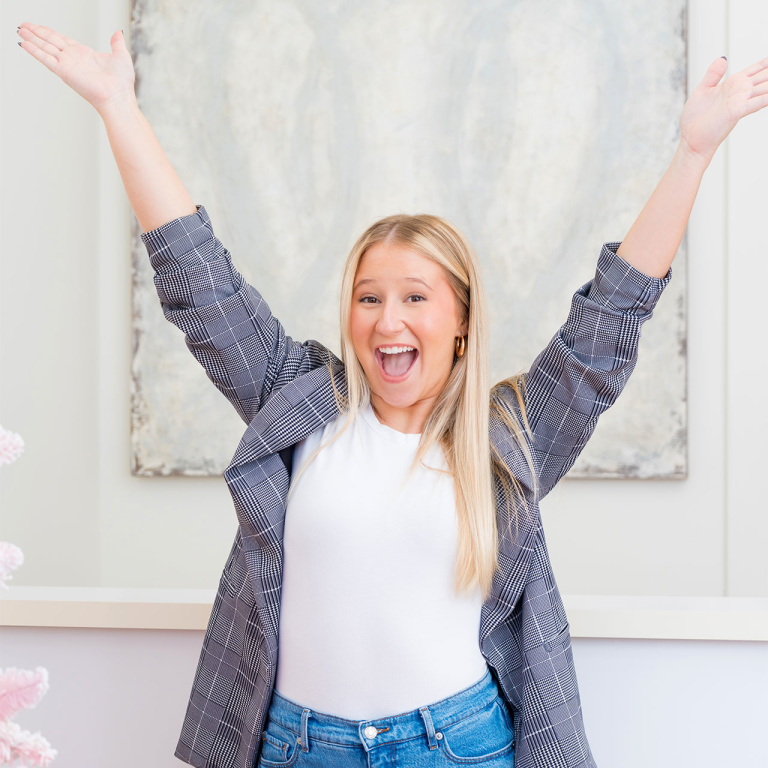 A woman with her hands in the air and a smile on her face.