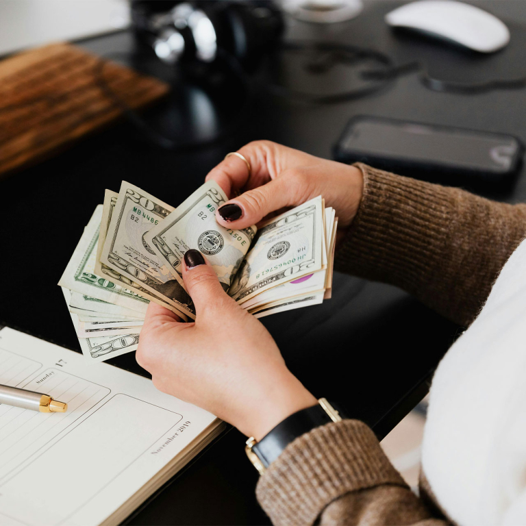 A person sitting at a desk counting money.