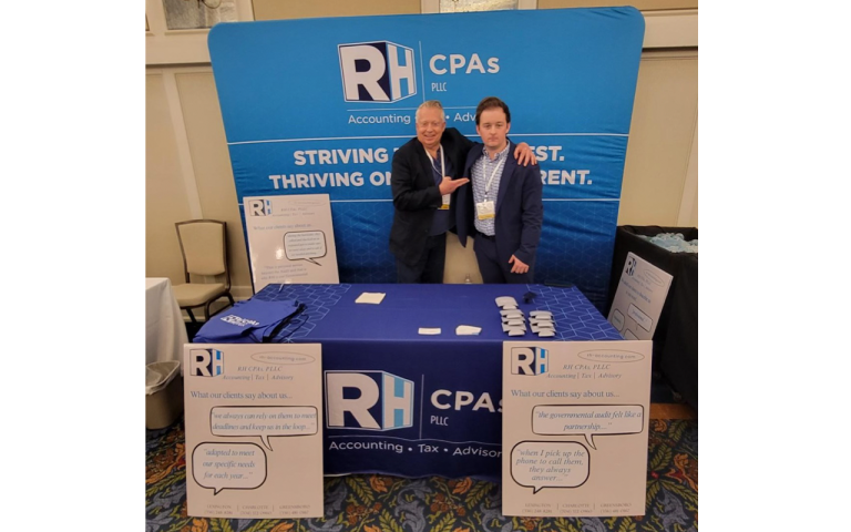 Two business professionals standing at a booth at a conference.
