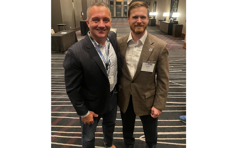 Two men posing for a photo in the lobby of a building.