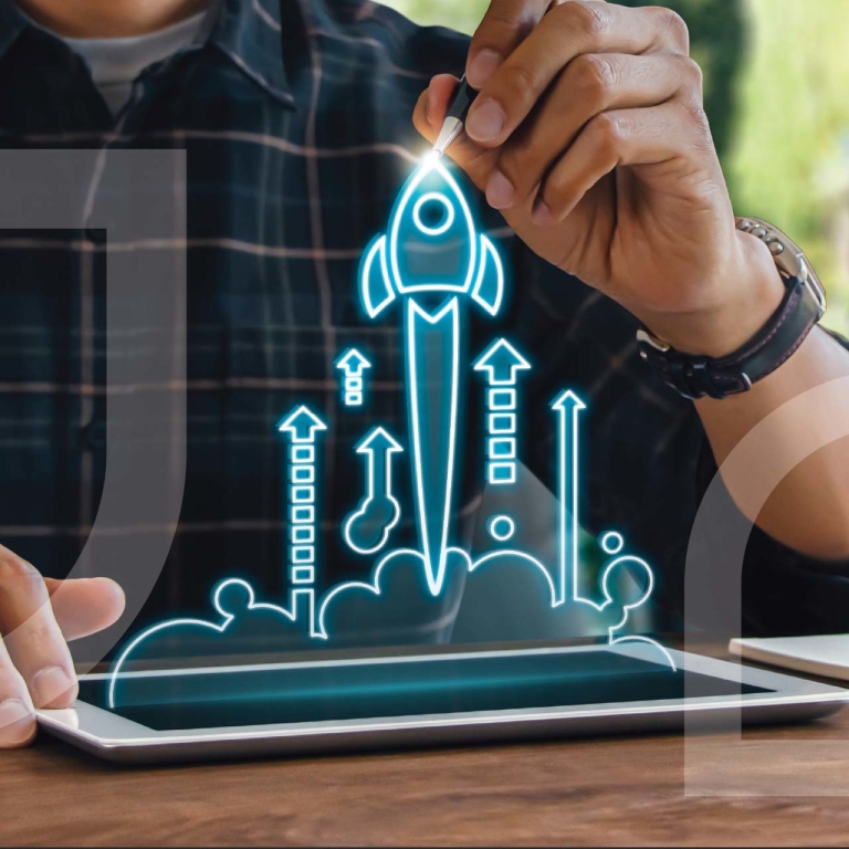 A man using a pen to illustrate a rocket ship using a tablet.