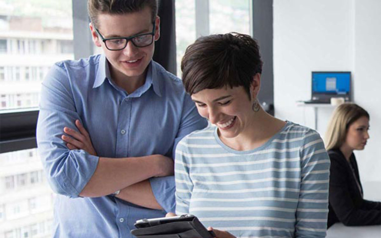 Two people looking at a tablet and smiling.