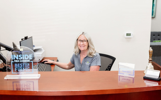 woman at a desk, smiling.