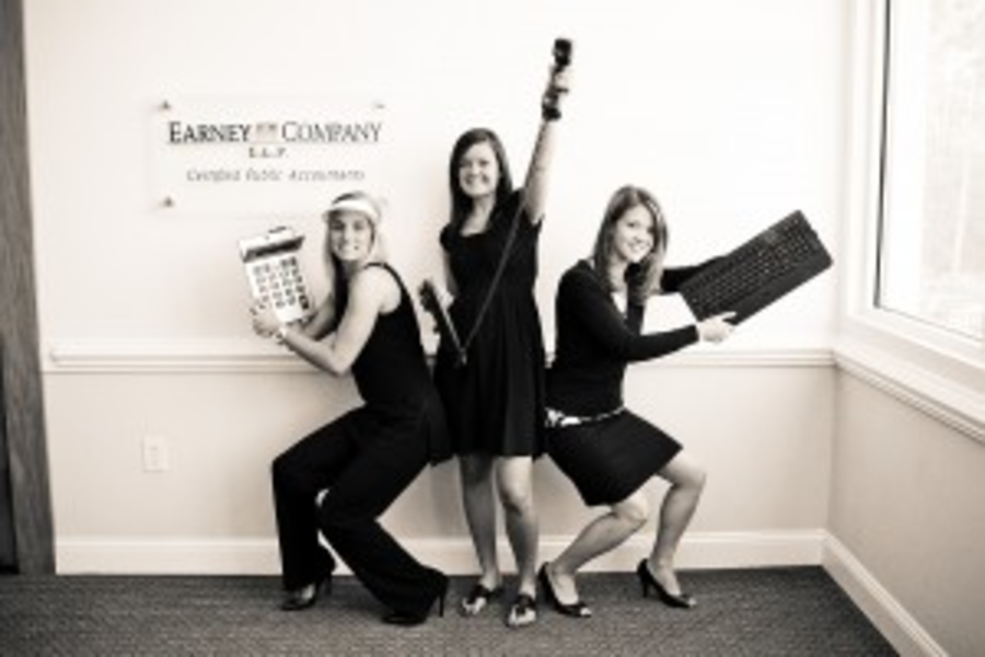 Three women posing with office items.