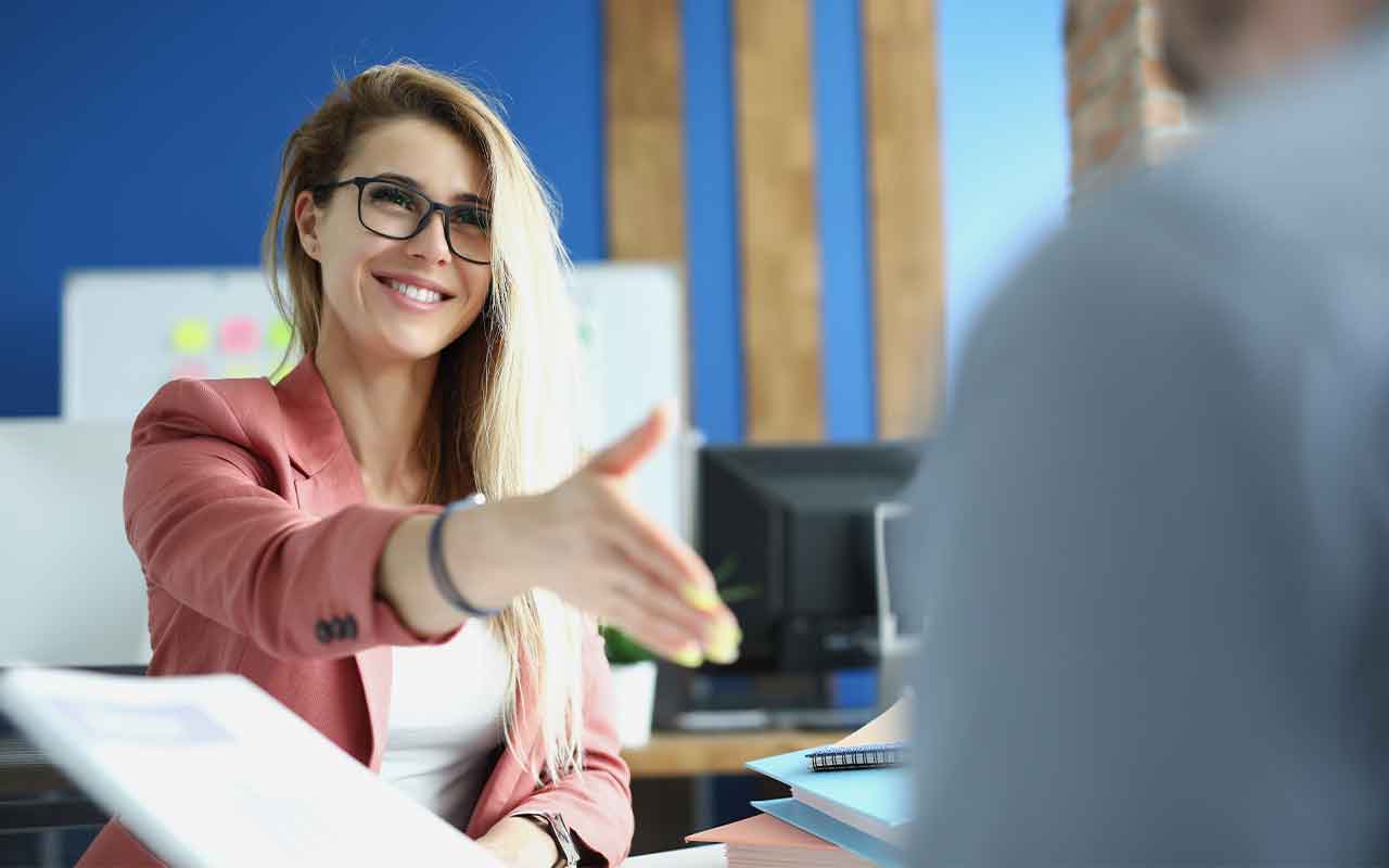 A female professional reaching her hand out for a handshake.