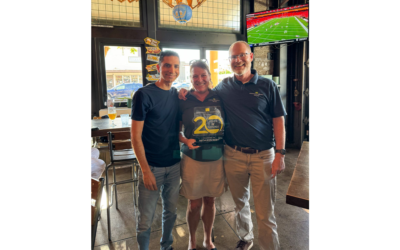 Three business professionals in a eatery, holding an award.