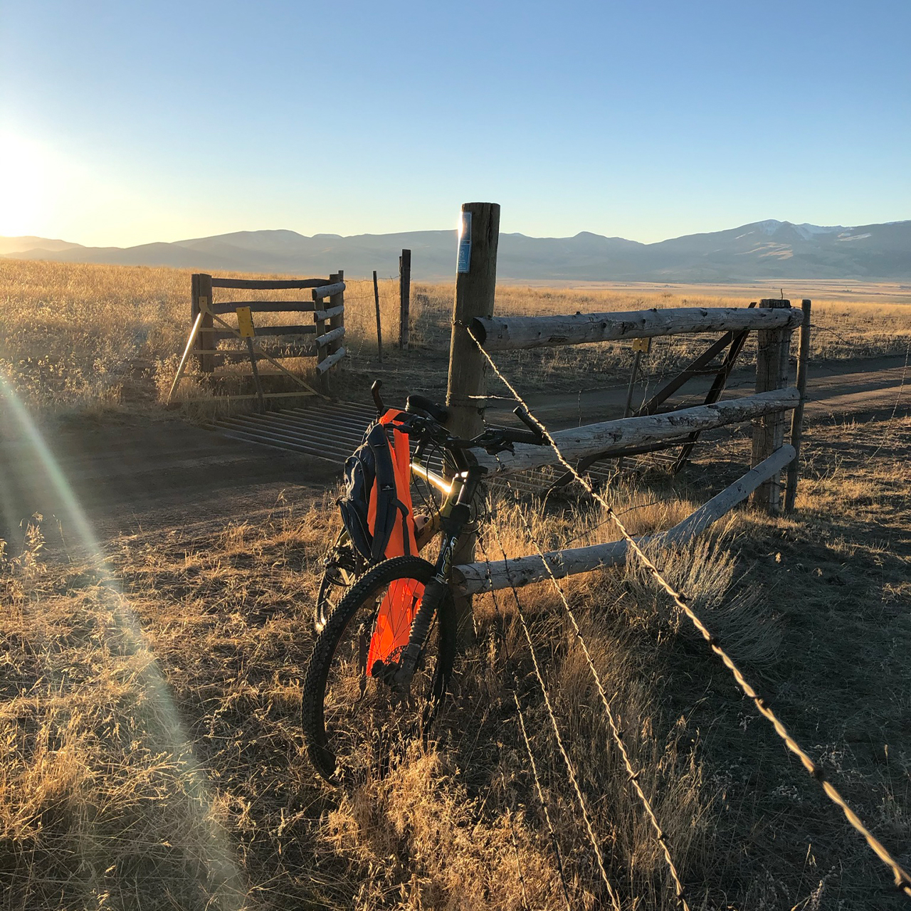 Bike next to a wooden post with a field and mountains behind it.