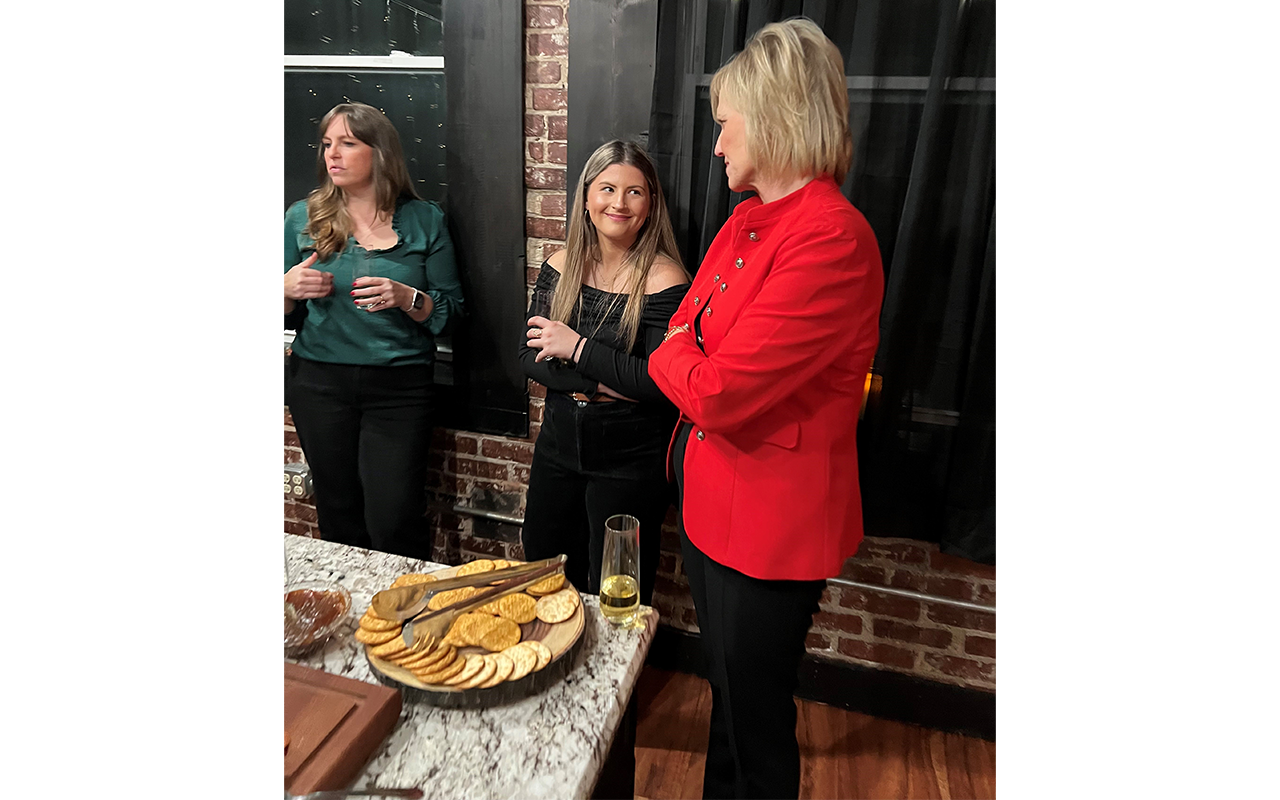 Three female business professionals at a Christmas party, eating and drinking.
