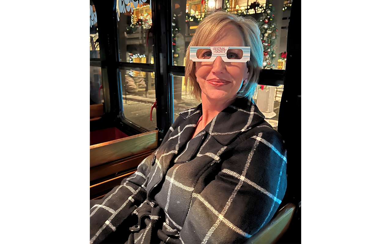 A woman on a trolly wearing Festive Lights glasses.