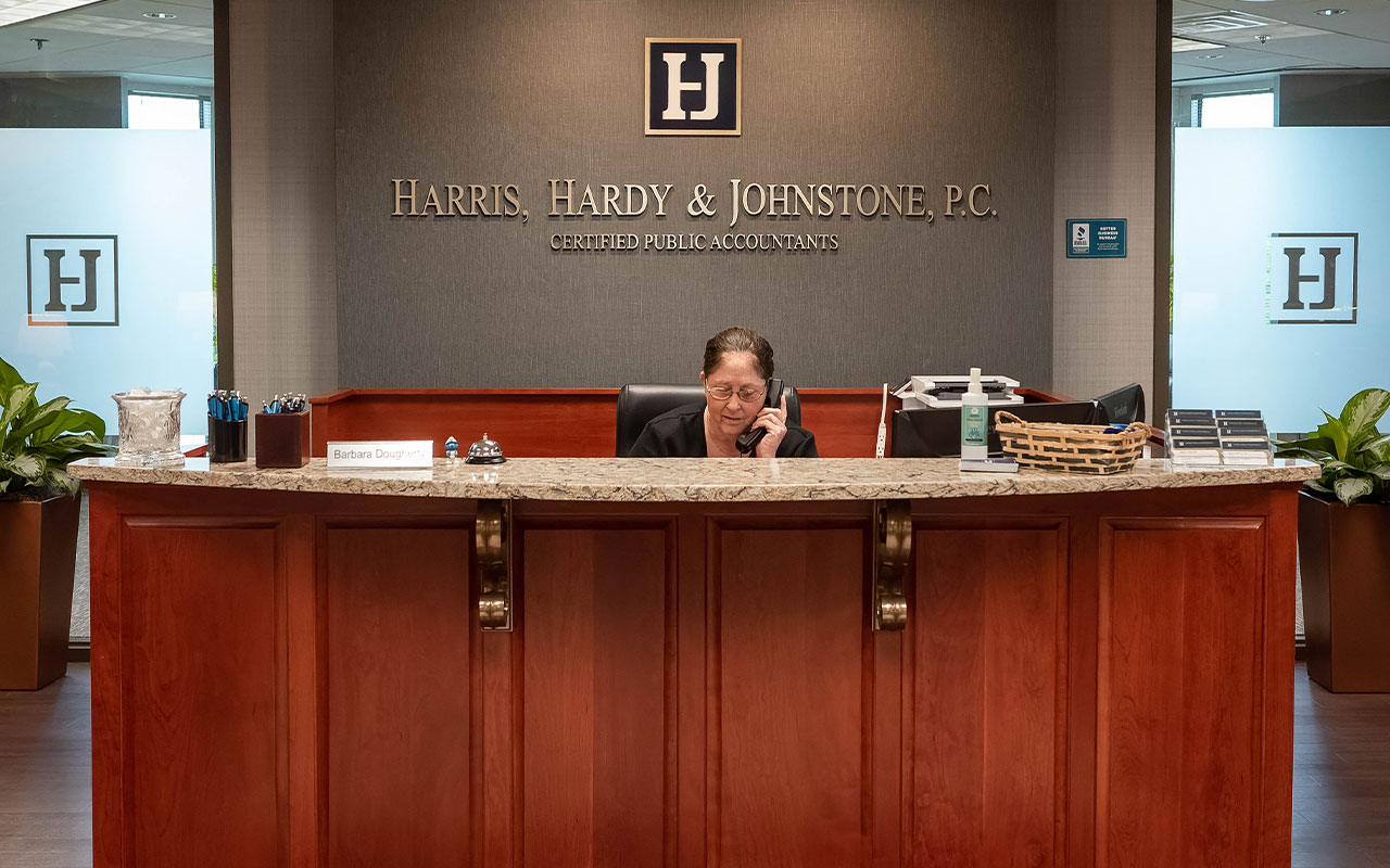 A female professional answering the phone at a desk in the lobby of an office building.