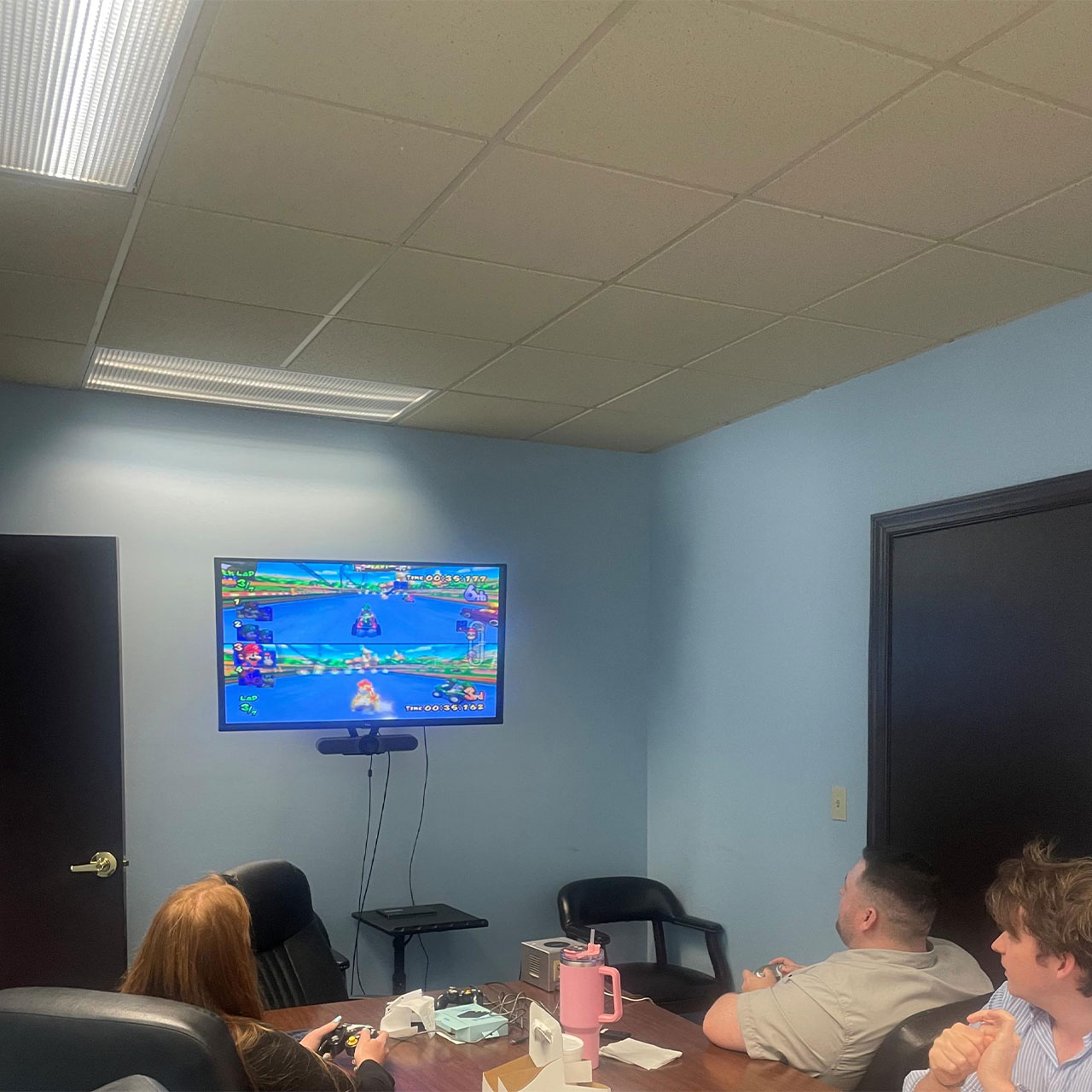 People playing Mario Kart in a conference room setting.