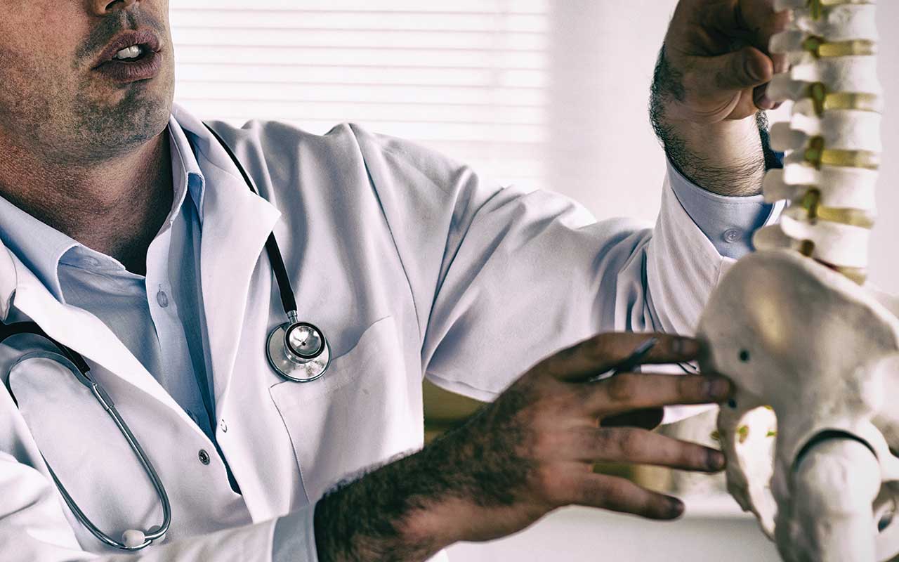 A chiropractor looking at a skeleton