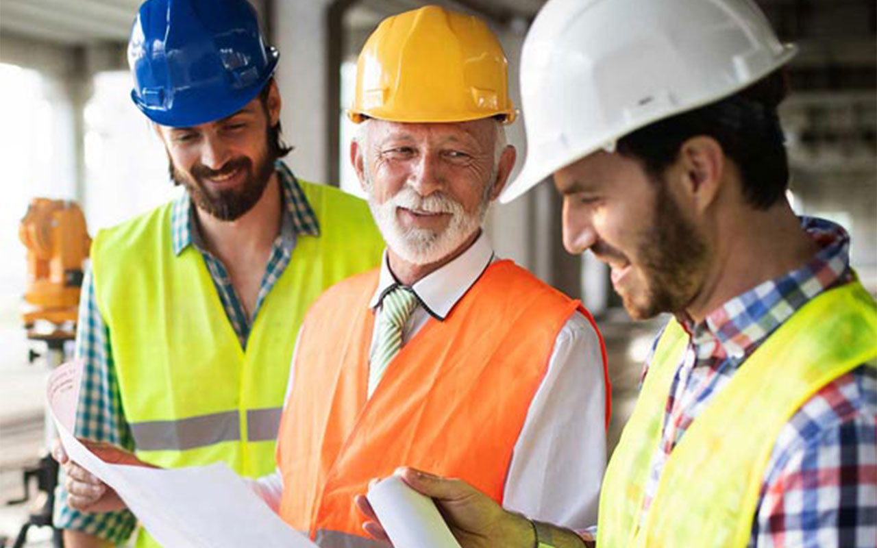 Three men in hard hats and safety vests smiling